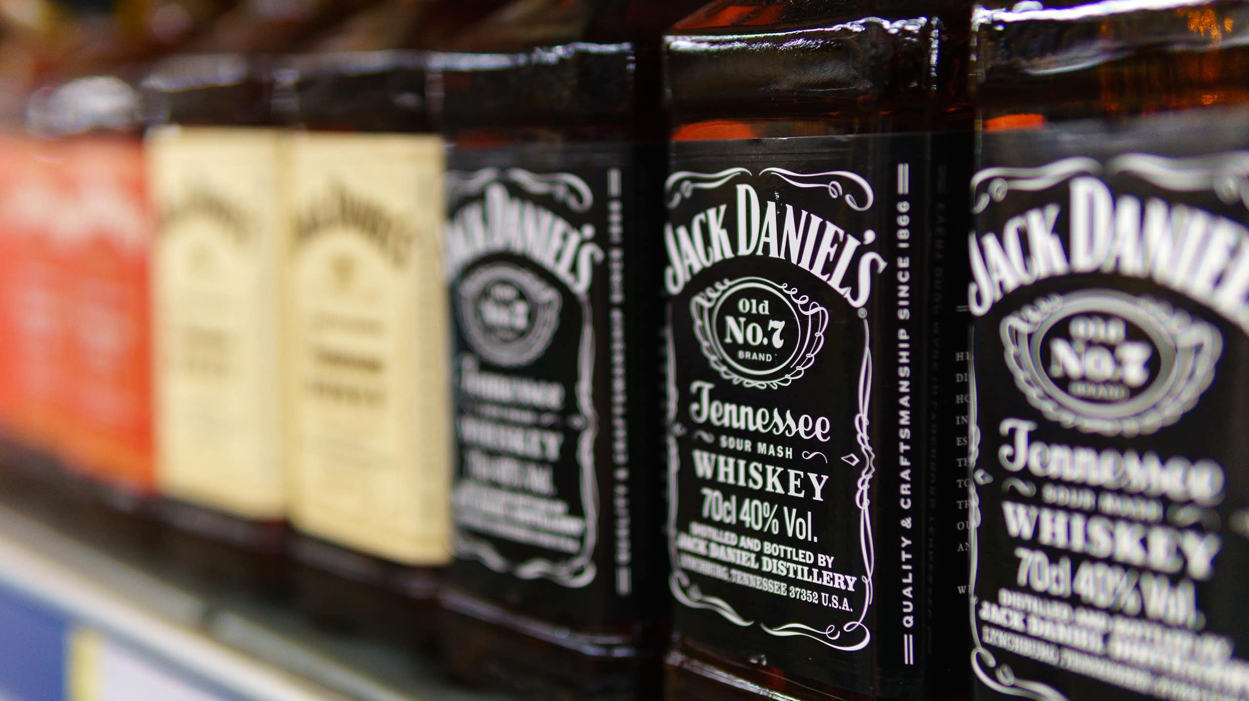 bottles of jack daniels lined up on a supermarket shelf.