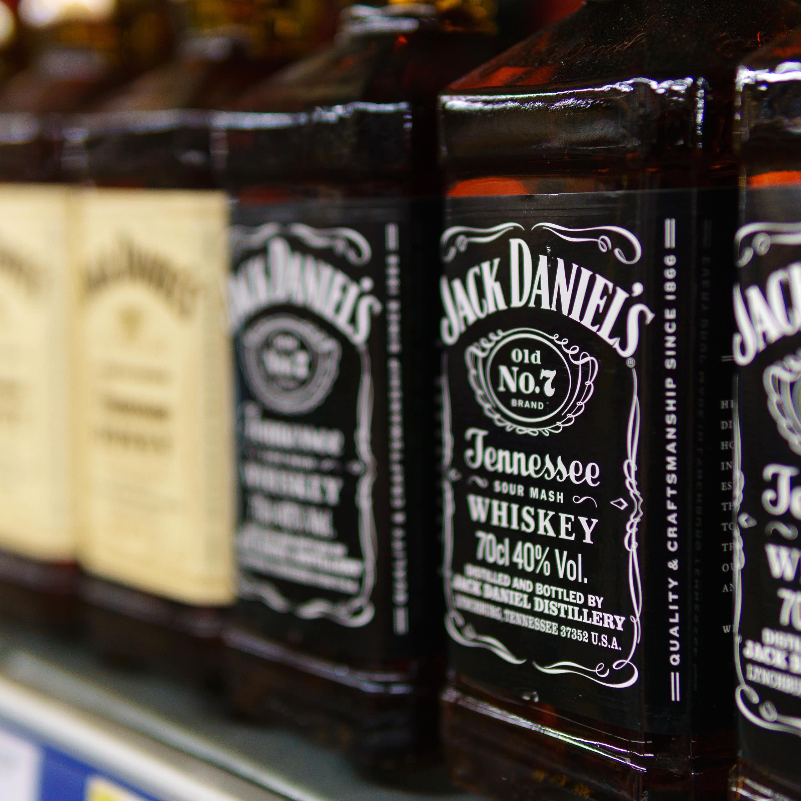 bottles of jack daniels lined up on a supermarket shelf.