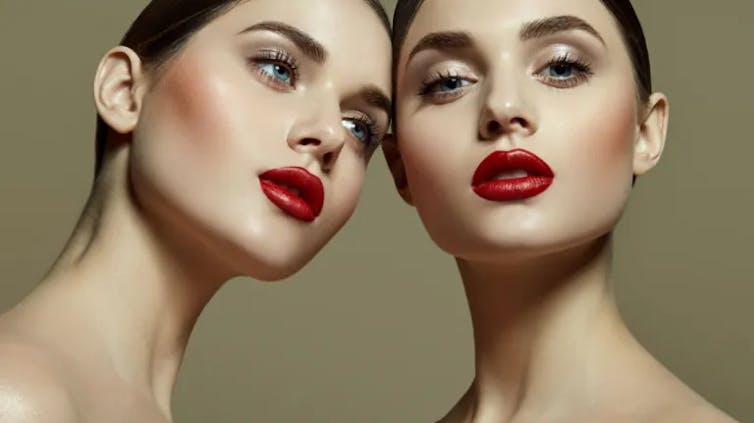 Dos mujeres con gemelos tocan la cabeza