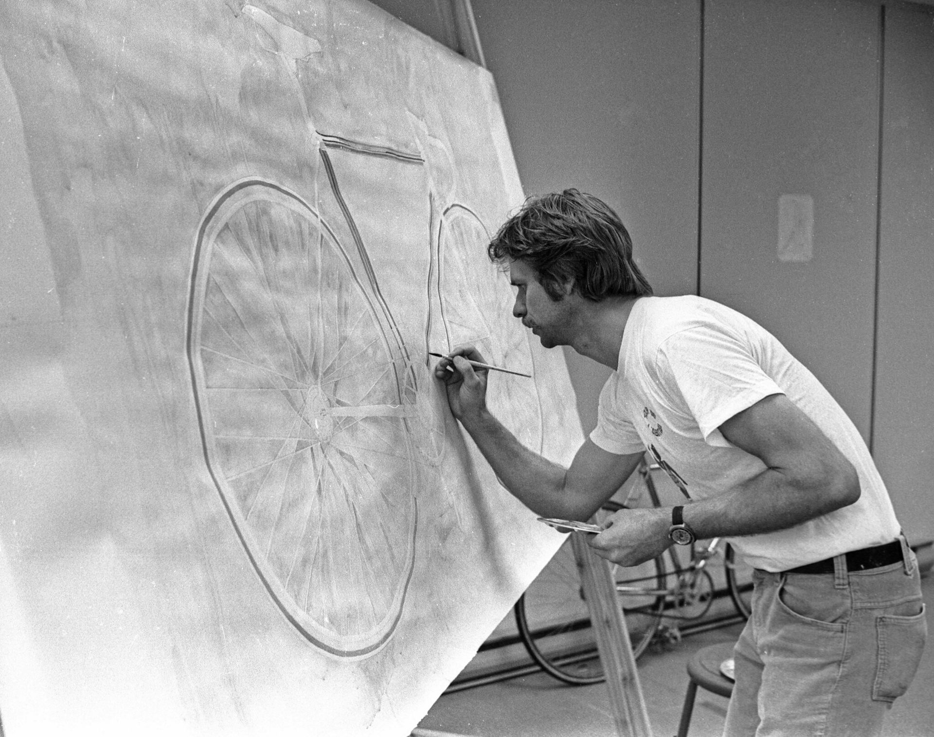 A man standing at an easel drawing a bicycle.