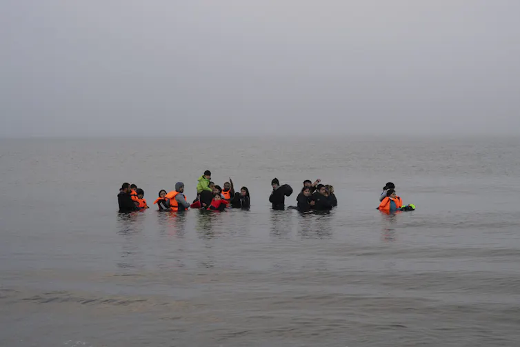 People stand waist deep in the ocean.