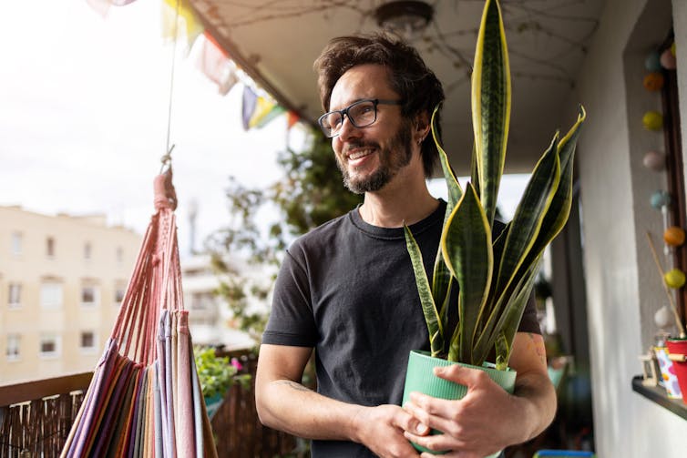 young man on balcony holding plant