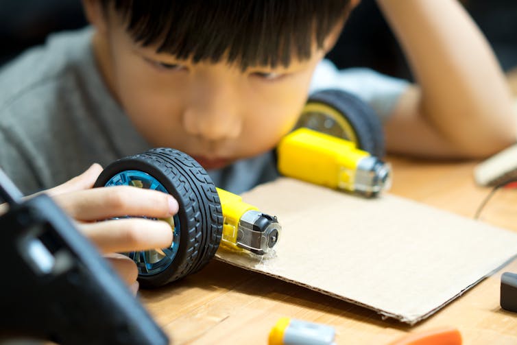 A young child plays with wheels and car components.
