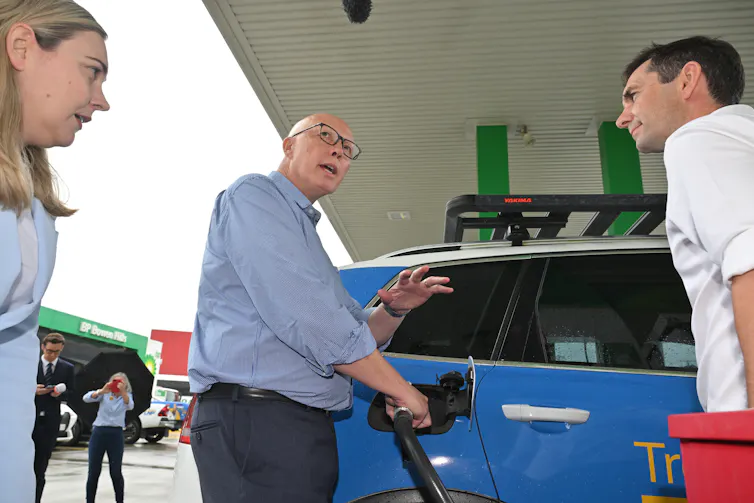 Peter Dutton fills up a car with fuel while talking to the press