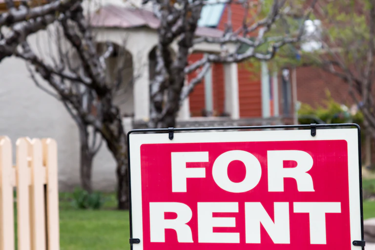 Red brick home with a "for rent" sign on the front fence