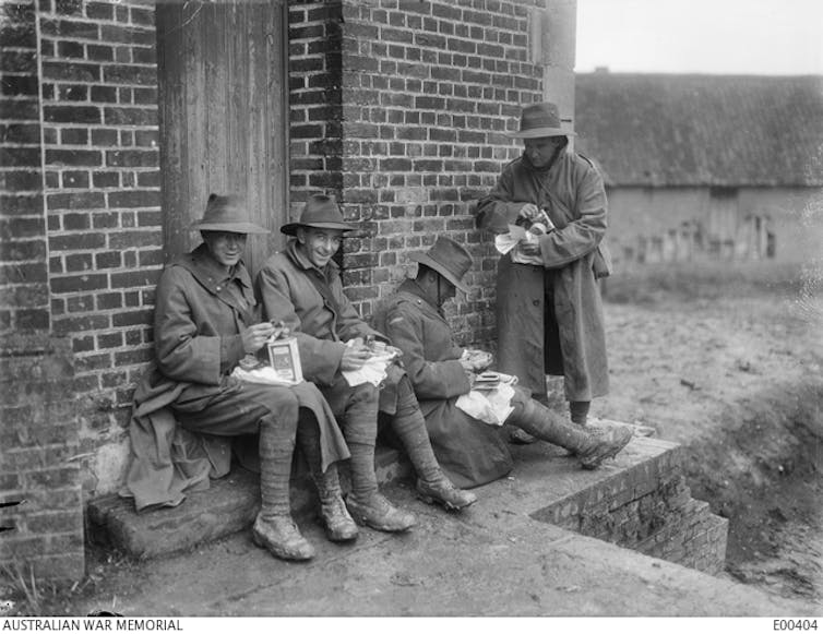Black and white photo: four men smile at their packages.