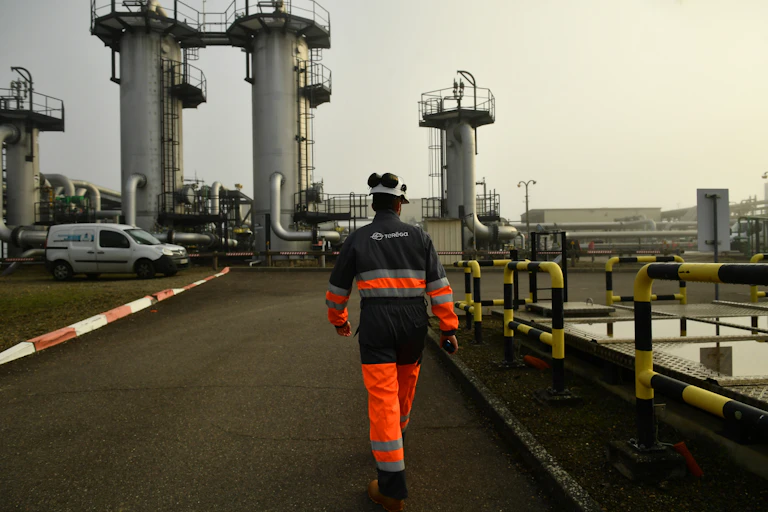 homme de dos en tenue de sécurité marche dans un environnement industriel