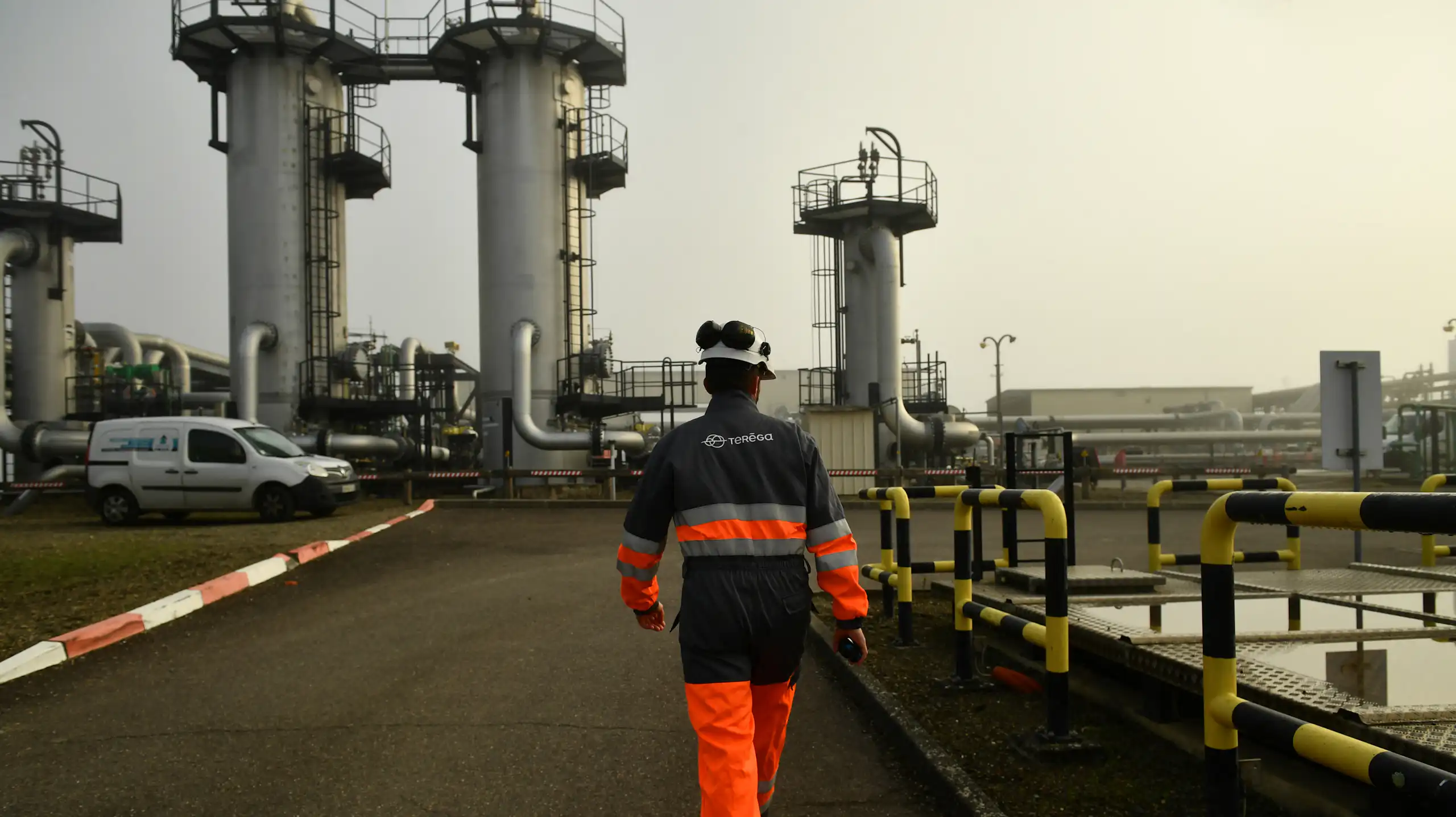 homme de dos en tenue de sécurité marche dans un environnement industriel