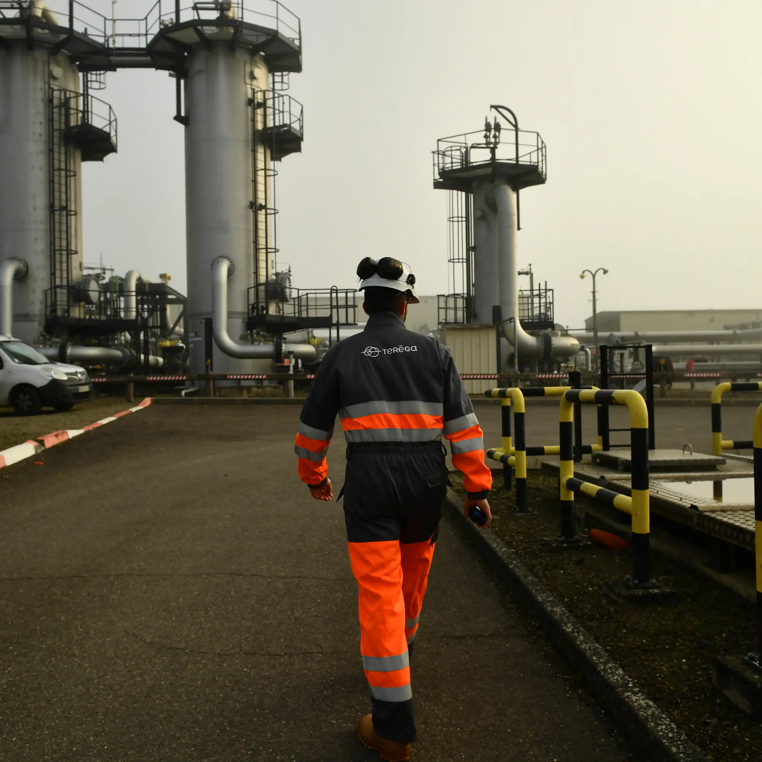 homme de dos en tenue de sécurité marche dans un environnement industriel