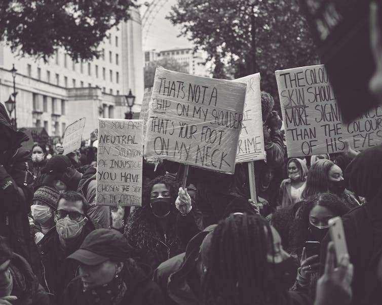 ‘Lived experience’ is valued in activism – however is it doing extra hurt than just right? 1 Black and white photo of marchers carrying handmade signs, one reading 'that's not a chip on my shoulder, that's your foot on my neck.'