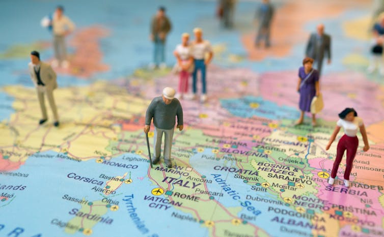Small figurines of people standing all over a map of Europe