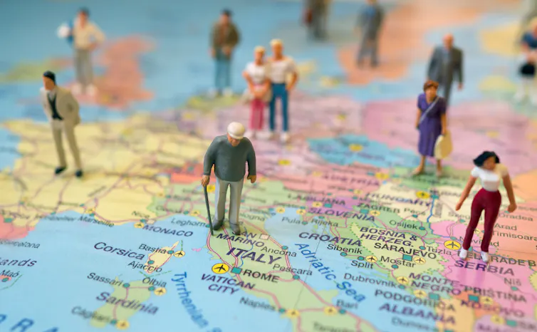 Small figurines of people standing all over a map of Europe