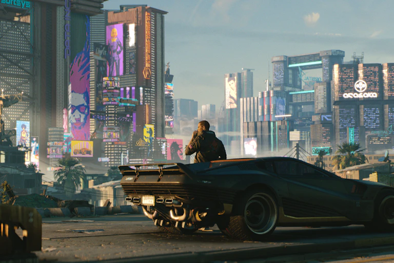 A man smoking on a car looking over a city.