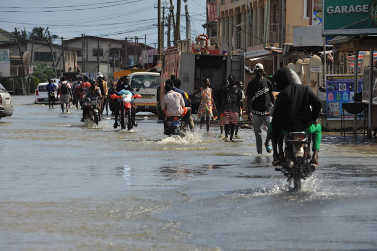 Pedestrians and motorcyclists on a flooded urban street
