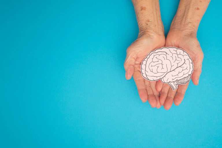 Older adults holding a paper cut-out of a brain in their hands.