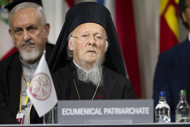 Ecumenical Patriarch Bartholomew of Constantinople stands at a podium ready to deliver a speech.