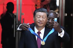 El hombre negro pone una medalla alrededor del cuello del hombre asiático.
