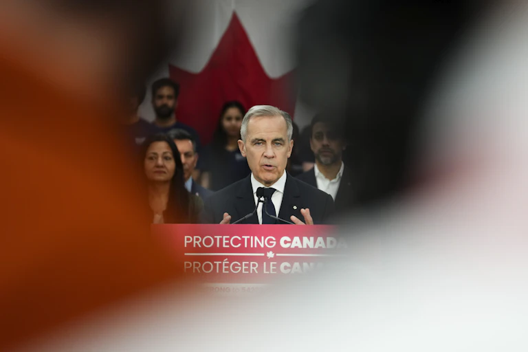 A white man with grey hair speaks from behind a podium
