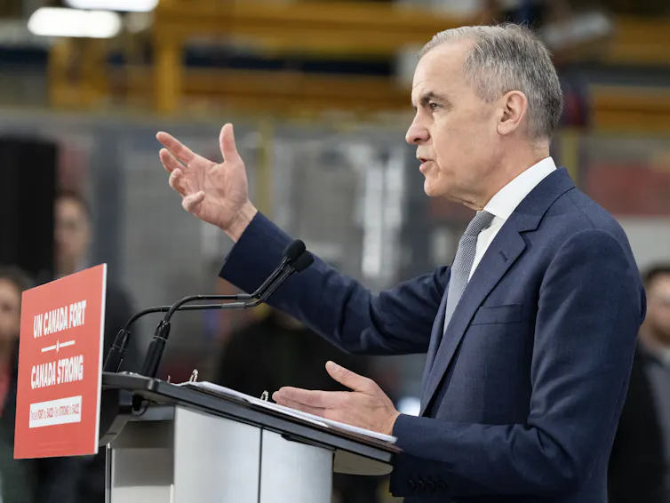 A white man with grey hair speaks from behind a podium
