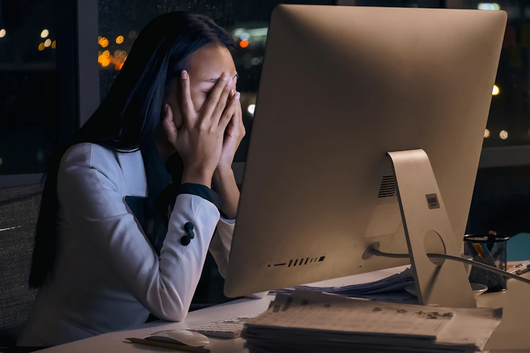 Stressed young woman using computer holding head in hands