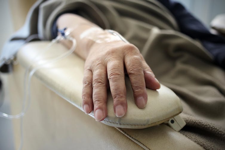 A person receiving chemotherapy. Only their arm is visible. A person receiving chemotherapy. Only their arm is visible.