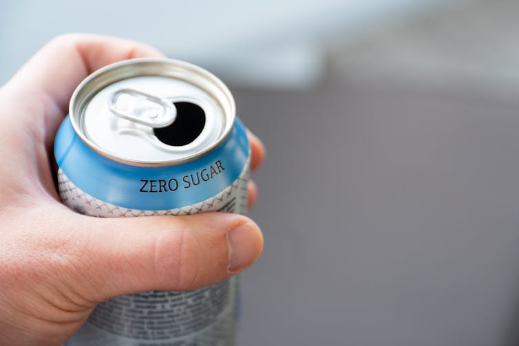 A person holds a can of zero sugar soft drink.