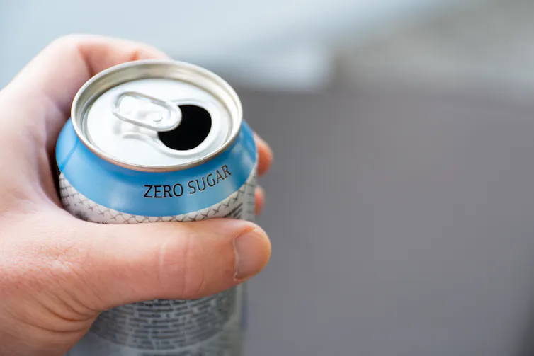 A person holds a can of zero sugar soft drink.