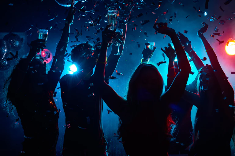 Silhouetted people dancing with drinks glasses