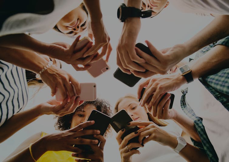 Circle of young people looking at mobile phones