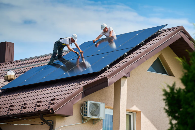deux ouvriers installent des panneaux solaires sur un toit