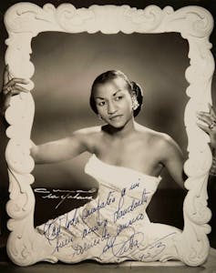 La mujer negra con un vestido blanco mantiene el marco alrededor de su cuerpo.