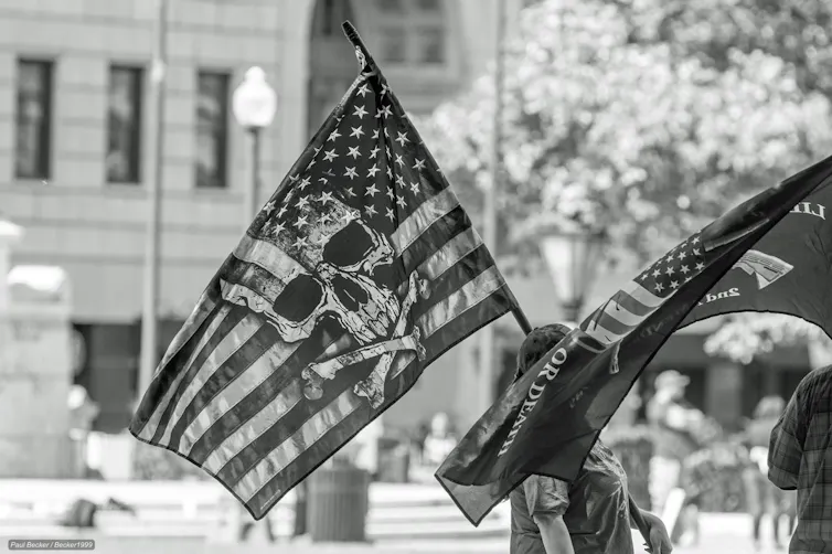 A black and white photo showing the skull and crossbones symbol transposed on the American Flag.