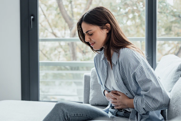 A woman holds her abdomen in pain.
