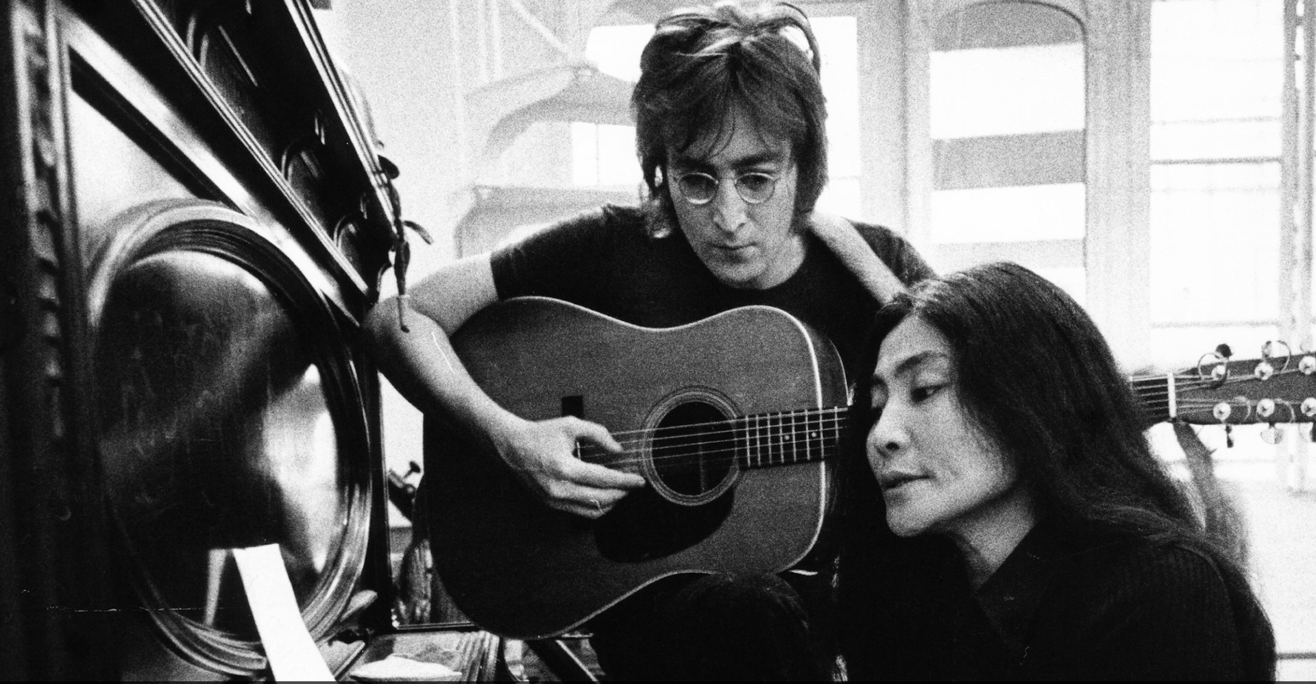 Yoko Ono playing piano and John Lennon playing guitar.
