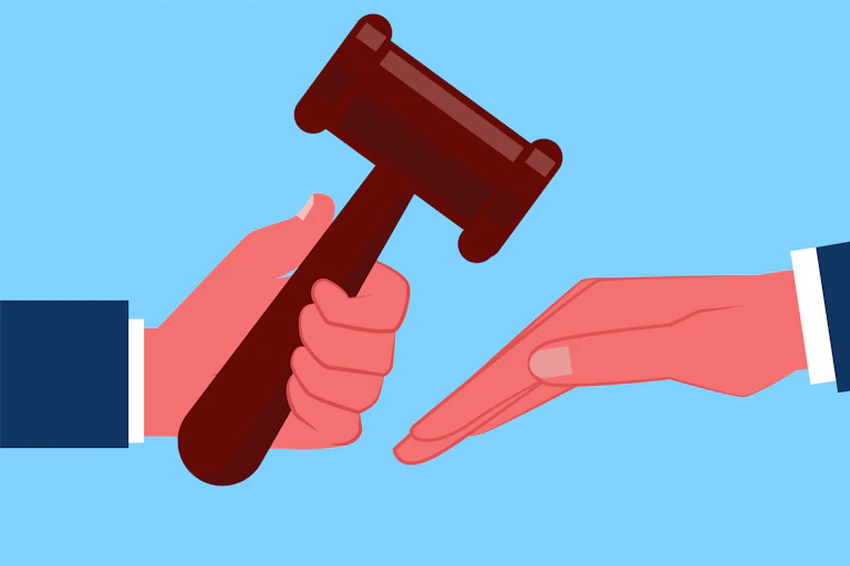 A hand holding a gavel over another hand.