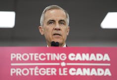 Donde los partidos se encuentran en el control de armas en las elecciones federales canadienses 1 Un hombre con un cabello gris corto habla en el micrófono detrás del banner rojo que lee Canadá en inglés y francés.