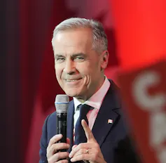 A man with a microphone in a suit and tie.