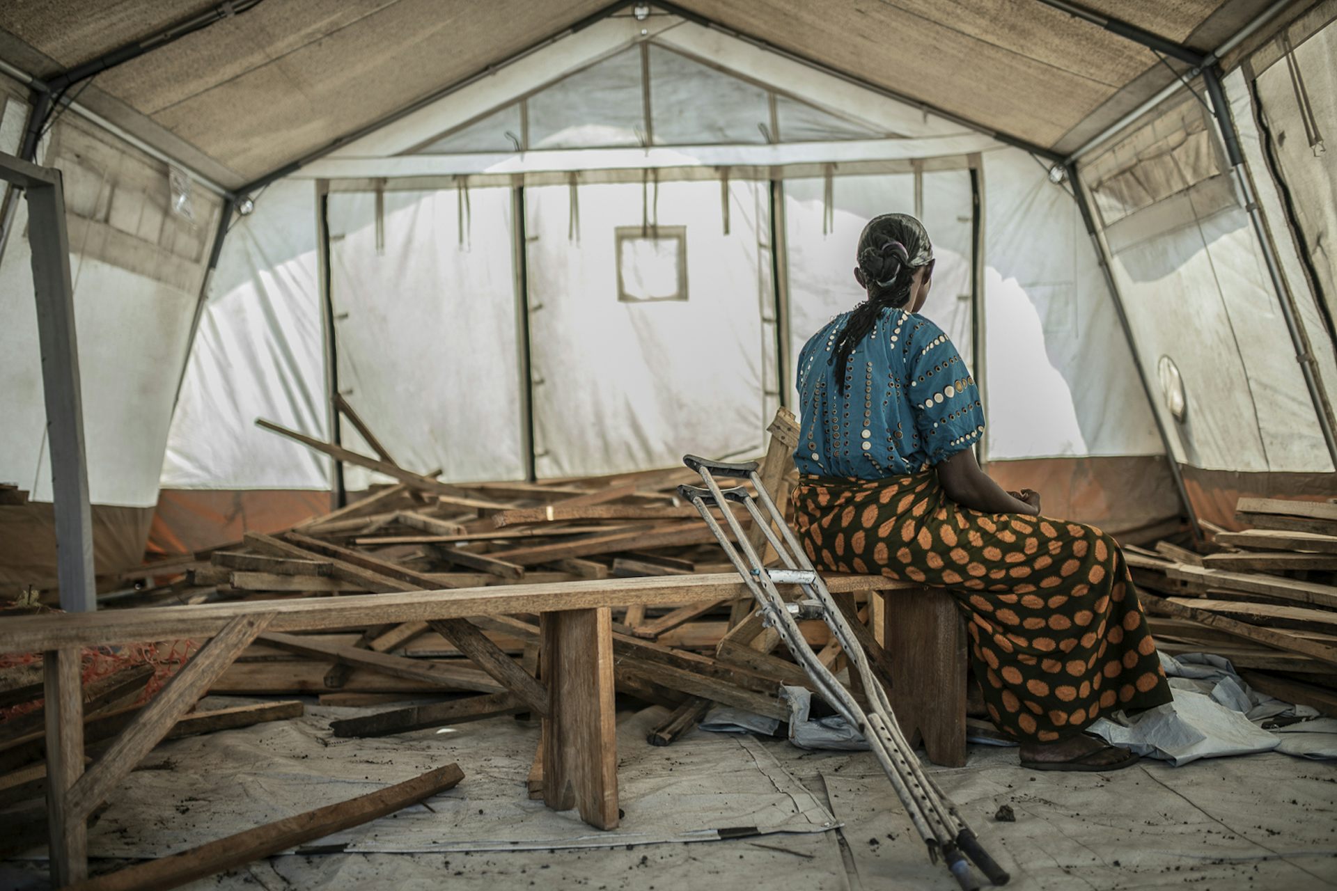 a woman sits with her back to the camera in a tent