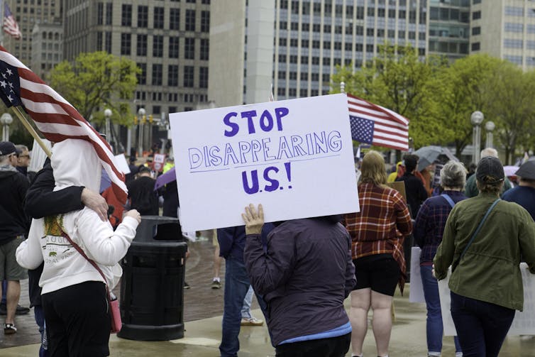 A sign held during a protest, which says 'STOP DISAPPEARING U.S.!'