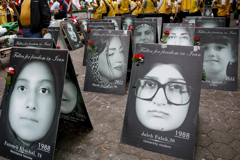 Protesters carry placards featuring the faces of Iranian women.