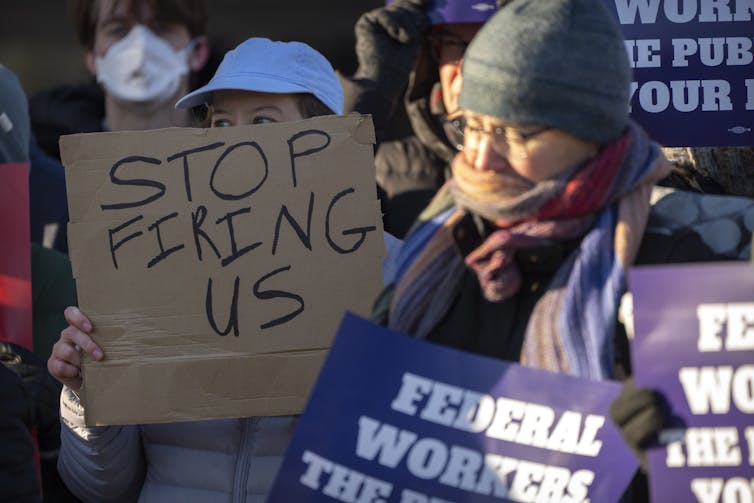 People take part in a protest against the firing of federal workers.