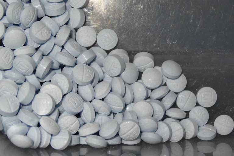 A pile of round blue pills against a chrome background