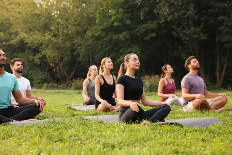 A group of people meditating outdoors.
