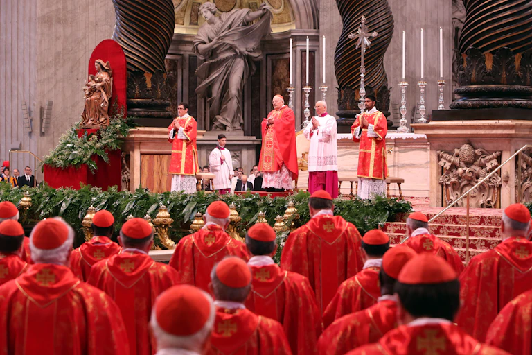 Several men in a red robe and red cap stand attend Mass.