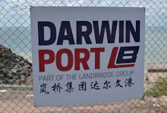 Sign attached to a wire fence. Beach in distant background