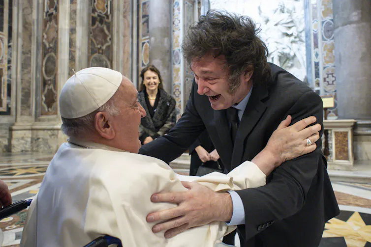 The two men have their hands on each others shoulders.