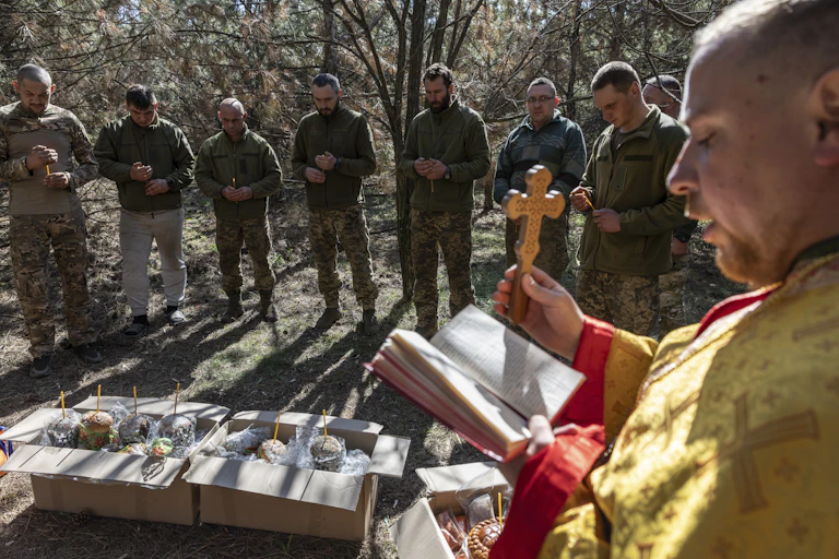 A priest holds up a cross as he blesses troops during an Easter Day service in Ukraine. April 20 2025.