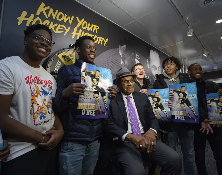 A row of Black boys smiling with an older Black man in the centre.