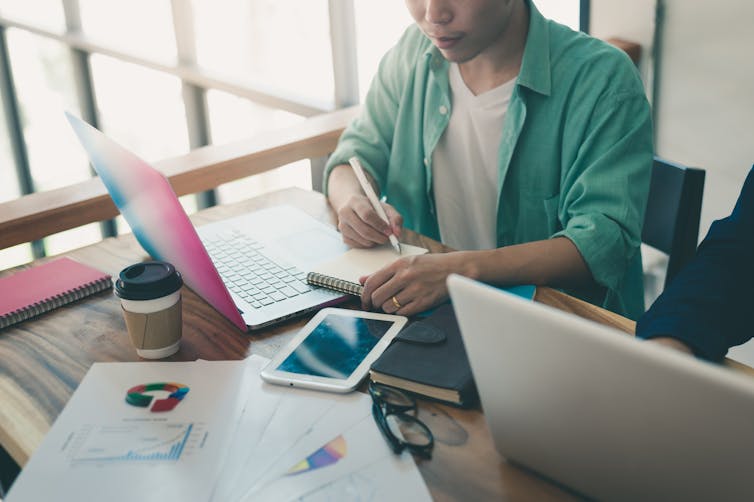 View of a young man sitting and working at a messy desk