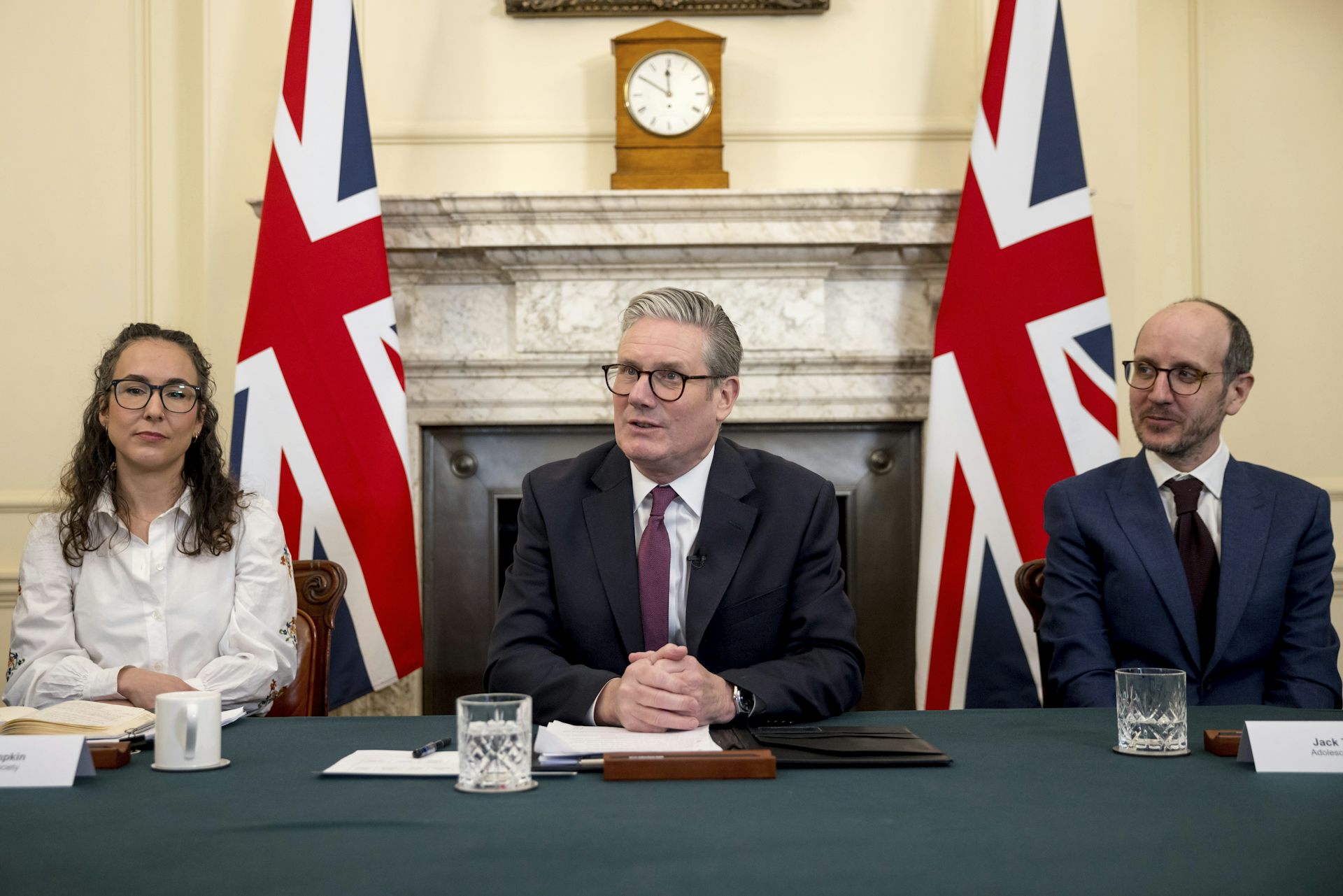 Trois personnes sont attablées devant des drapeaux anglais
